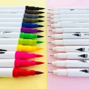 Fileira de canetas coloridas de ponta dupla organizadas simetricamente. À esquerda, aparecem as pontas tipo pincel (brush) e à direita as pontas finas (fineliners), dispostas sobre um fundo de papel amarelo e rosa.