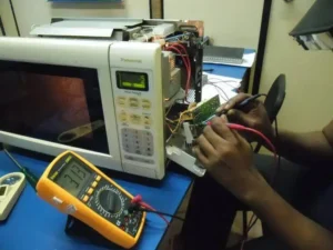 Técnico realizando teste e medição no circuito de controle da placa eletrônica de um micro-ondas Panasonic com multímetro digital - Radar Prático
